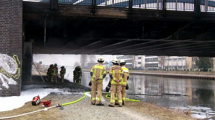 Feuerwehrmänner stehen am 26.03.2018 an einer brennenden Brücke im Berliner Stadtteil Charlottenburg (Quelle: rbb)