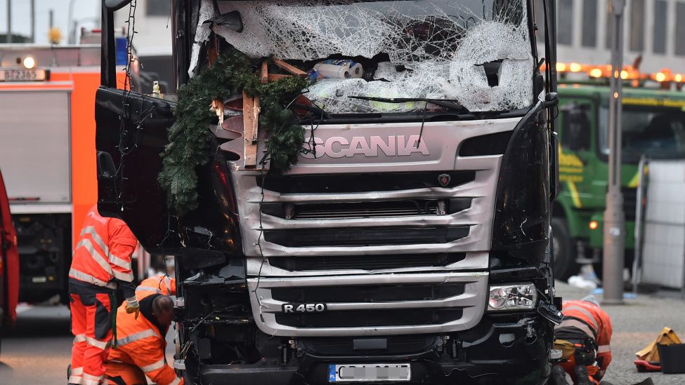 Mitarbeiter eines Abschleppunternehmens hocken am 20.12.2016 am Breitscheidplatz in Berlin neben einem beschädigten LKW, der abgeschleppt werden soll. (Quelle: dpa/Britta Pedersen)