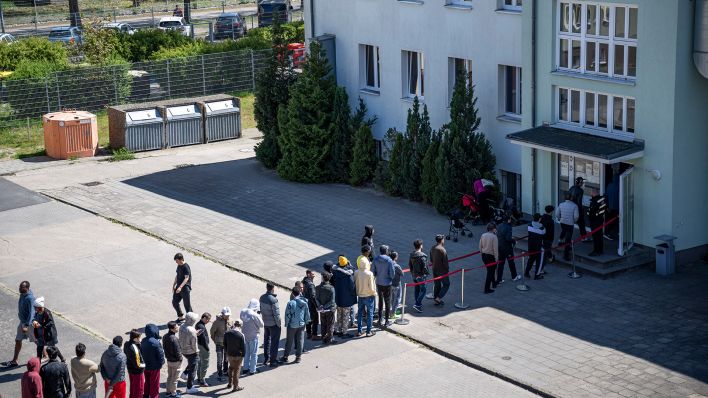 Migranten stehen in einer Schlange in der Erstaufnahme-Einrichtungen (EAE) des Landes Brandenburg in Eisenhüttenstadt. (Quelle: dpa/Hannes P Albert)