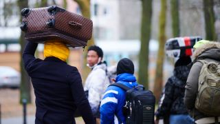 Flüchtlinge tragen ihre Koffer auf dem Kopf während sie ins Ankunftszentrum Reinickendorf gehen. (Quelle: dpa/Annette Riedl)