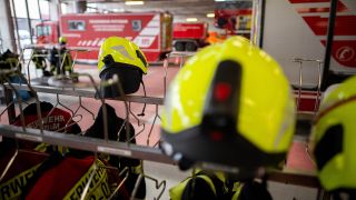 Symbolbild: Einsatzkleidung von Feuerwehrleuten hängt während der Vorstellung zur Bilanz von Feuerwehr und Rettungsdienst in der Wagenhalle. (Quelle: dpa/Gollnow)