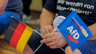 Symbolbild:Ein AfD-Anhänger hält auf der Wahlkampfveranstaltung eine Deutschland- und eine AfD-Fahne in seinen Händen.(Quelle:picture alliance/dpa/A.Arnold)