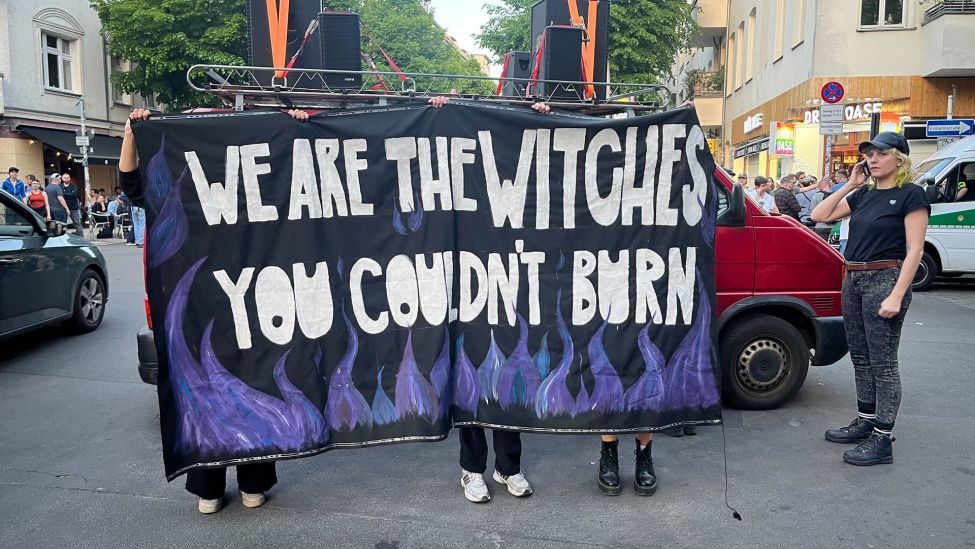 Demonstrant:innen stehen hinter einem Demo-Plakat mit der Aufschrift "We are the Witches you couldn't burn" vor der queerfeministischen Demonstration "Take back the night" am 30.04.2024 auf dem Boxhagener Platz in Berlin (Quelle: rbb).