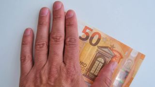 Symbolbild: Ein 50 Euro Geldschein wird mit der Hand berührt.(Quelle: picture alliance/imageBROKER/Fotowerkstatt-ks)