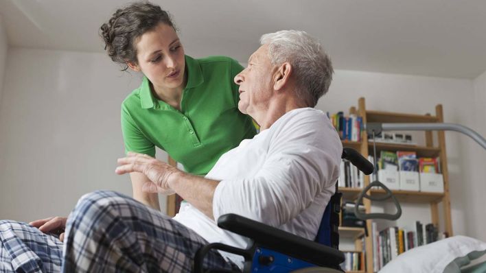 Ambulante Pflege, Mann im Rollstuhl unterhält sich mit Pflegerin.