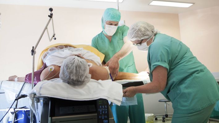 Zwei Chirurgen operieren einen Patienten - In Berlin will ein Bündnis den Personalmangel in der Pflege bekämpfen (Bild: dpa/Benoist).