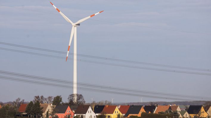 Eine Windkraftanlage zeichnet sich ab hinter einer Wohnsiedlung