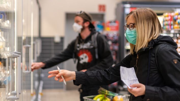 Kunden tragen beim Einkaufen im Supermarkt einen Mundschutz (Bild: dpa)