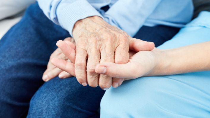 Krankenschwester oder Altenpfleger hält Hand einer alten Frau