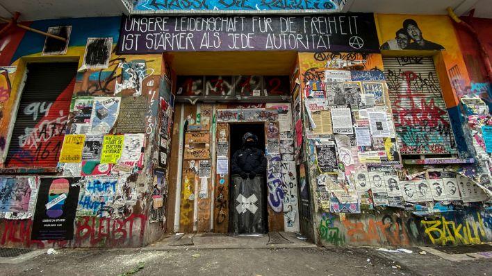 Ein Polizeibeamter steht in einem Hauseingang in der Rigaer Straße. (Bild: dpa)