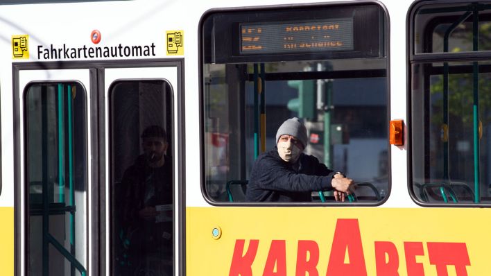 Ein Mann mit Atemschutzmaske und Mütze sitzt in einer leeren Straßenbahn, die durch die Potsdamer Innenstadt fährt (Bild: dpa / Sören Stache)