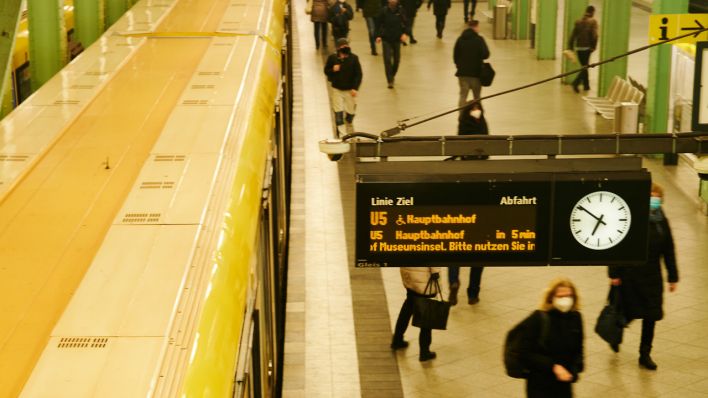 Menschen laufen am Bahnsteig des Alexanderplatz während eine U-Bahn in den Bahnhof einfährt (Bild: dpa)