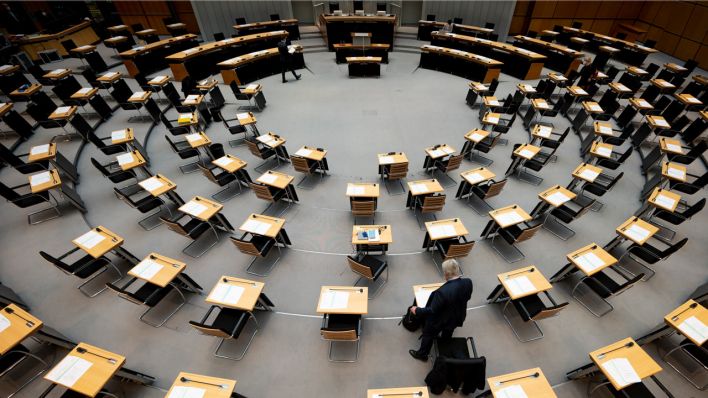 Ein Abgeordneter steht im fast leeren Plenarsaal des Berliner Abgeordnetenhaus vor einer Sitzung.