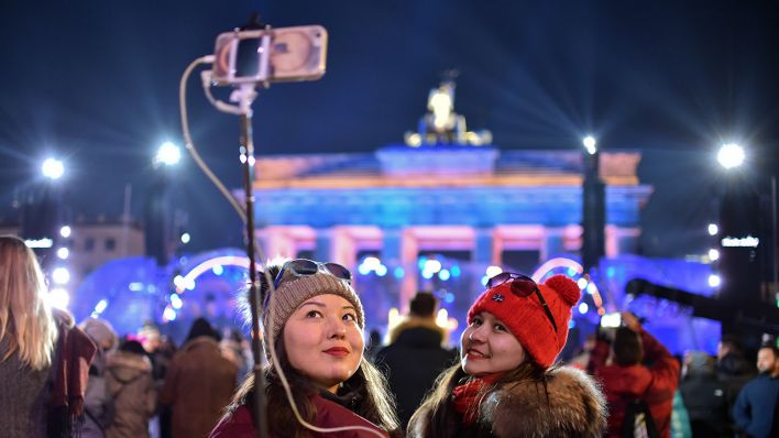Zwei Frauen aus Kasachstan machen ein Selfie vor dem Brandenburger Tor in Berlin.
