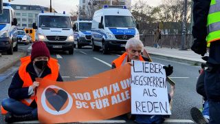 Mitglieder der Gruppe "Letzte Generation" haben sich auf einer Straße festgeklebt. Auf einem Plakat steht "Lieber wegsperren als reden" (Bild: picture alliance/ dpa)