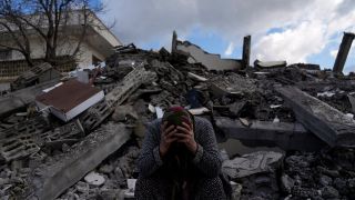 Eine Frau sitzt auf Trümmern, nach dem verheerenden Erdbeben.