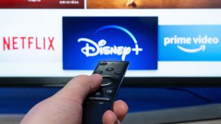 Die Logos der Streaminganbieter Netflix, Disney+ und Amazon Prime Video sind auf einem Fernseher zu sehen.