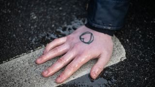 Ein Klimaaktivist der Gruppe "Letzte Generation" hat sich an einer Hauptverkehrsstraße mit der Hand auf den Asphalt geklebt.