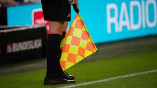 Linienrichter mit Fahne bei einem Spiel der Fußball-Bundesliga (Bild. IMAGO / Sven Simon)