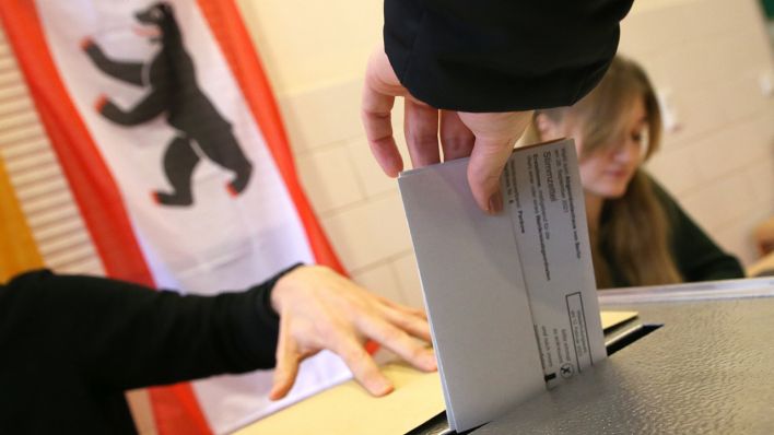 Eine Hand wirft einen Stimmzettel für die Wahl zum Berliner Abgeordnetenhaus in die Wahlurne (Bild: dpa / Wolfgang Kumm)