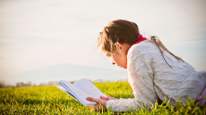 Ein Mädchen liest im Freien ein Buch [colourbox]