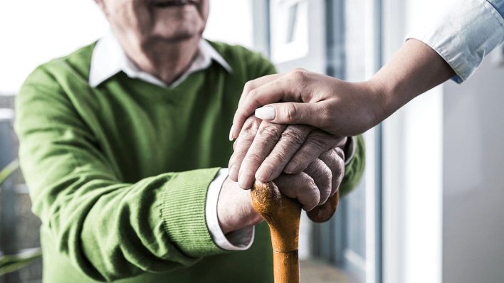 Eine Altenpflegerin unterstützt einen hilfsbedürftigen Mann in einem Altenheim © imago/Westend61
