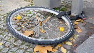 Fahrraddiebstahl: Nur das Hinterrad eines Fahrrads liegt angeschlossen an einem Pfosten in Berlin