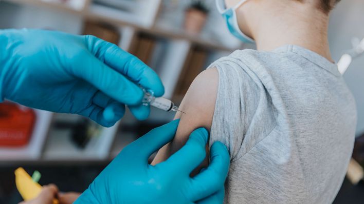 Ein Arzt impft einen Jungen gegen das Coronavirus (Symbolfoto)