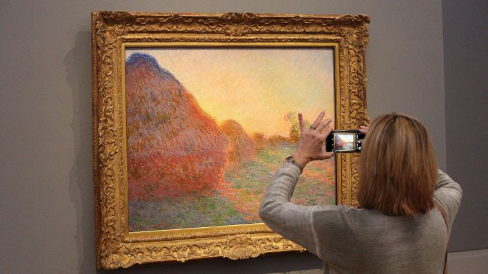 Archivbild: Eine Frau fotografiert das Gemälde "Getreideschober" von Monet