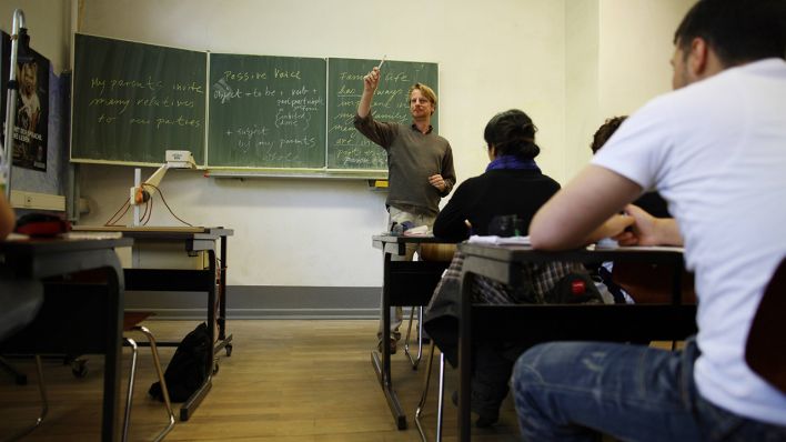 Ein Lehrer unterrichtet in einer Schulklasse © imago images/Gerhard Leber