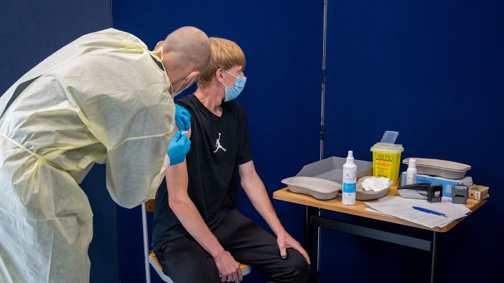"In einem mobilen Impfzentrum an einer Berufsschule wird ein Schüler geimpft"; © dpa/ Christophe Gateau