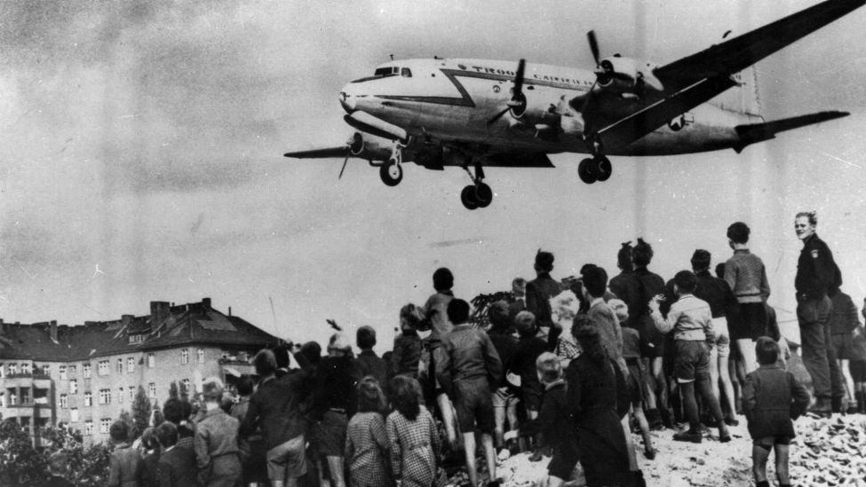 Eine C-54 „Skymaster“ der US-Luftwaffe, die 1948 auf dem Berliner Luftwaffenstützpunkt Templehoff landet, wird von einer Gruppe blockierter Berliner beobachtet (Bild: picture alliance / ASSOCIATED PRESS )