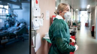 Josephin Kampmann, Gesundheits- und Krankenpflegerin, steht auf dem Gang der Corona-Intensivstation des Universitätsklinikums Essen und zieht Schutzkleidung an. Bild: Fabian Strauch/dpa
