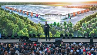 Elon Musk, Tesla-Chef, steht zum Tag der offenen Tür auf eine Bühne der Tesla Gigafactory. Bild: Patrick Pleul/dpa-Zentralbild