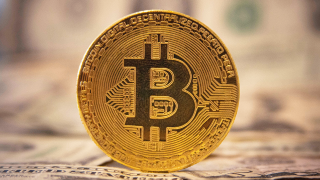 Bitcoin Münze auf Dollarscheinen (Quelle: picture alliance / NurPhoto | Nicolas Economou)