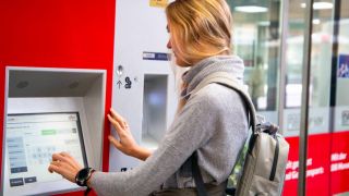 Vor einem Ticketautomaten der Deutschen Bahn steht eine Frau und kauft ein Ticket (Quelle: imago images/Hermann Agenturfotografie)