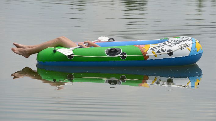 Ein Jugendlicher liegt in einem Schlauchboot in einem Badesee (Quelle: dpa/Arne Dedert)