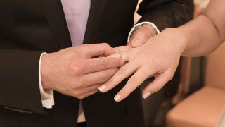 Ein Bräutigam steckt seiner Braut den Ehering an den Finger. (Quelle: imago/Westend61)