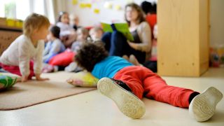 ILLUSTRATION: Kinder liegen und sitzen in einer Kindertagesstätte (Quelle: dpa/Monika Skolimowska)
