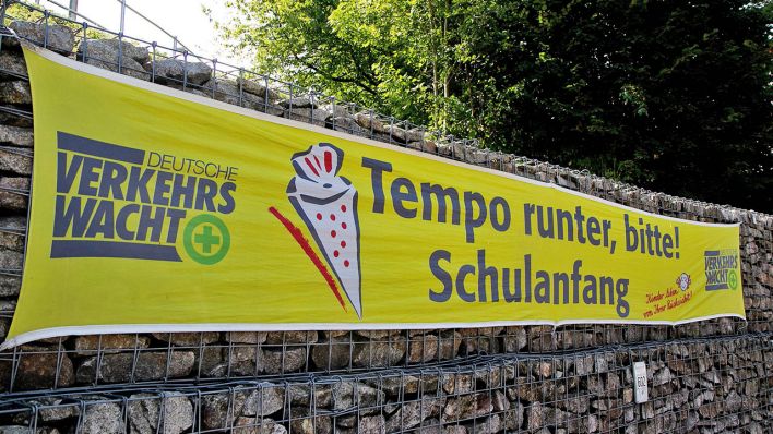 Plakat mit der Aufschrift "Tempo runter, bitte! Schulanfang!" (Quelle: imago/Eibner)