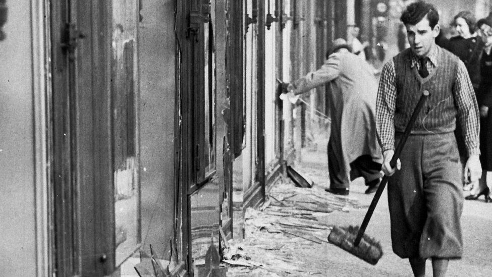 Ein historisches Foto vom 10.11.1938 zeigt einen Mann, der am Tag nach der "Reichskristallnacht", dabei ist die Scherben eines zerbrochenen Fensters eines jüdischen Geschäfts in Berlin aufzukehren. (Bild: dpa)