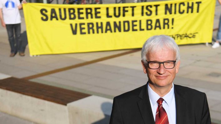 Jürgen Resch, einer der Geschäftsführer der Deutschen Umwelthilfe (DUH), steht vor Beginn der Verhandlung des Verwaltungsgerichts über ein mögliches Diesel-Fahrverbot vor einem Greenpeace-Plakat mit der Aufschrift <<Saubere Luft ist nicht verhandelbar !>>. (Quelle: dpa/Dedert)