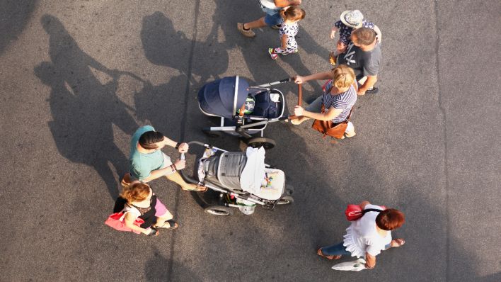 16.09.2018, Berlin: Zwei junge Familien mit Kindern begegenen sich, als sie über eine Straße gehen. Bei der einen Familie schiebt die Mutter den Kinderwagen, bei der anderen der Vater, Foto: Wolfram Steinberg/dpa