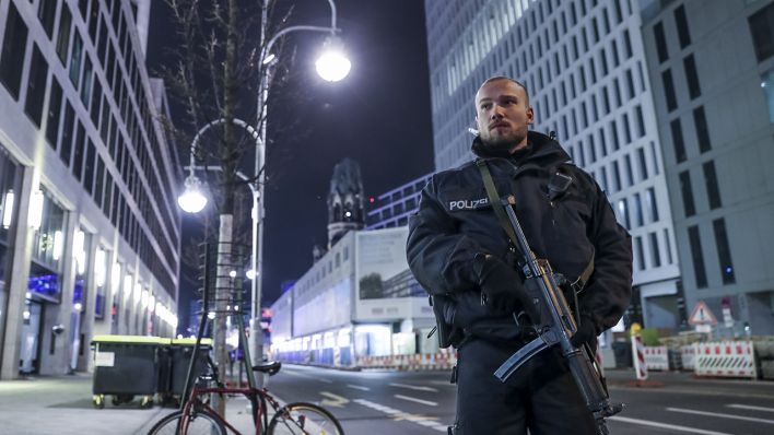 Ein Polizist steht am 19.12.2016 mit einer Maschinenpistole bewaffnet am Weihnachtsmarkt am Breitscheidplatz in Berlin kurz nach dem Terroranschlag. (Quelle: dpa/Michael Kappeler)