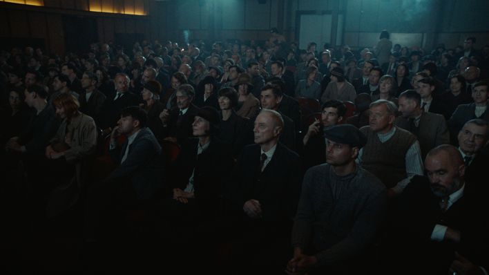 Standbild aus Babylon Berlin: Das Publikum verfolgt gespannt die Wochenschau, die in einem kleinen Kinosaal vorgeführt wird. (Quelle: X Filme | ARD Degeto | sky | Beta)