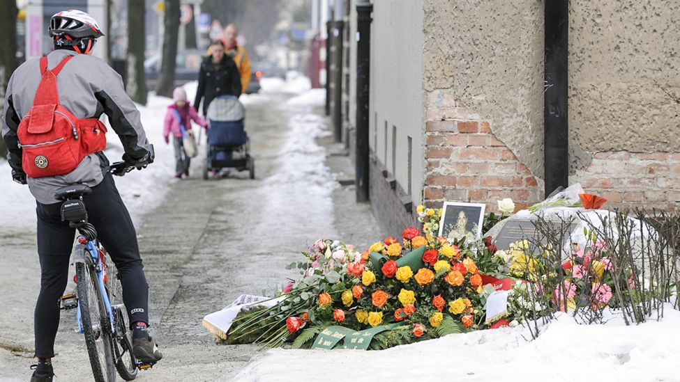 Ein Radfahrer betrachtet am Sonntag (07.02.2010) in Berlin die neben dem Gedenkstein für die am 07.02.2005 ermordete Hatun Sürücü liegenden Blumen und Kränze. (Quelle: dpa/Stache)