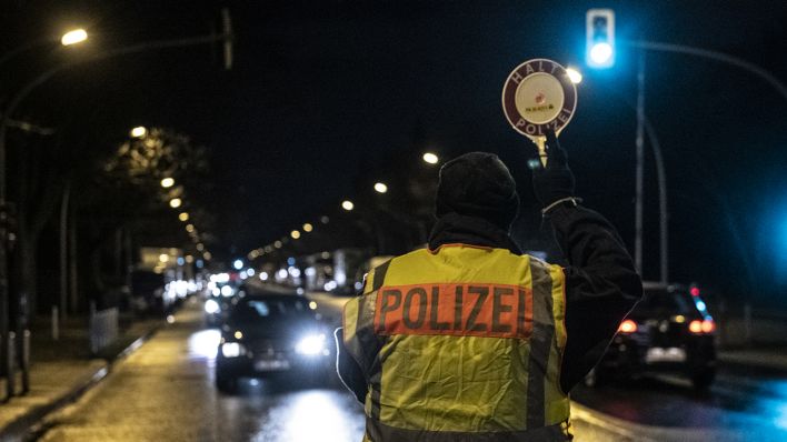 Ein Polizist winkt am 18.03.2019 im Stadtteil Neukölln ein Fahrzeug aus dem Verkehr. Die Berliner Polizei hat am Montagabend mehrere Luxusautos im Norden Neuköllns kontrolliert. (Quelle: dpa/Paul Zinken)