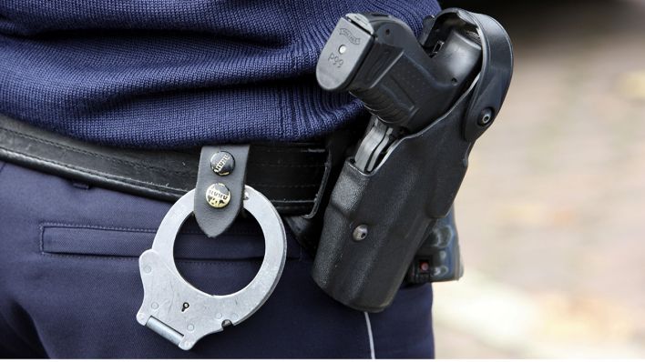 Ein Polizist mit Handschellen und Dienstwaffe. Quelle: dpa/Jochen Tack