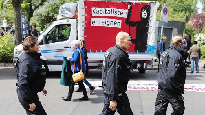 Polizeibeamte gehen zu Beginn der Demonstration «my Gruni» im Grunewald an einem Schild mit der Aufschrift «Kapitalisten enteignen» vorbei. (Quelle: dpa/Nietfeld)