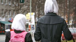 Junge Muslimas mit weißen Kopftüchern auf einem Fußweg im Bezirk Kreuzberg (Quelle: dpa/Steinberg)
